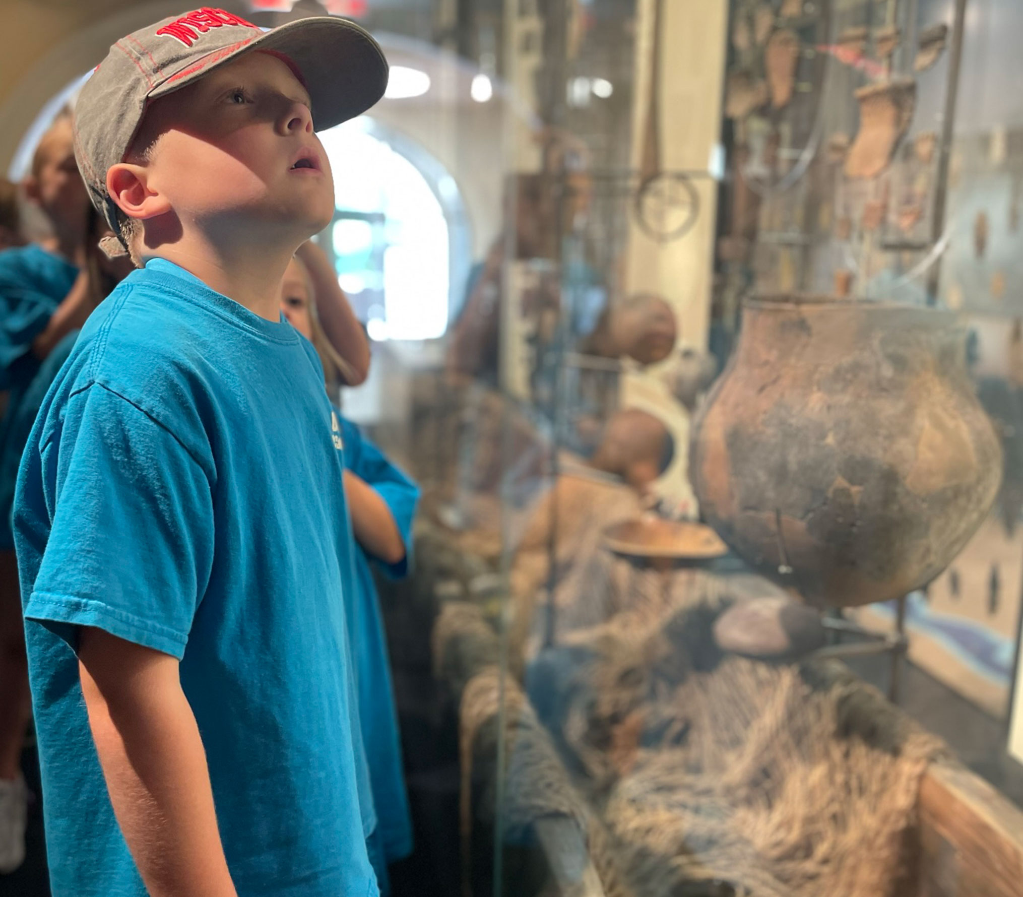 A child inspecting artifacts in the People of the Waters exhibit