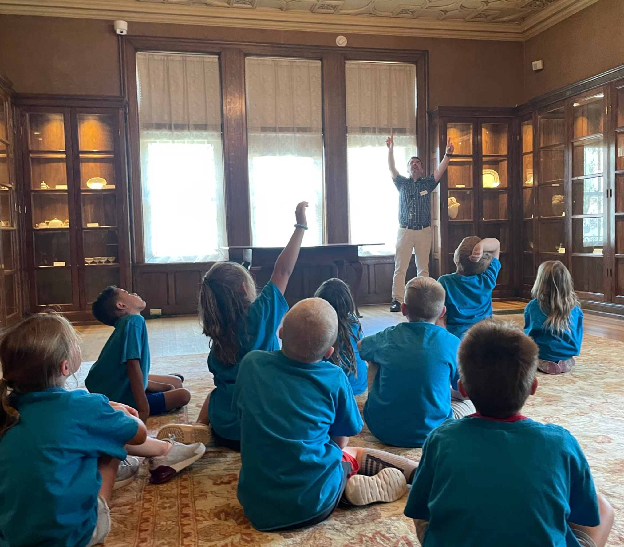 Oshkosh Public Museum staff member working with a field trip group in the Historic Sawyer Home library