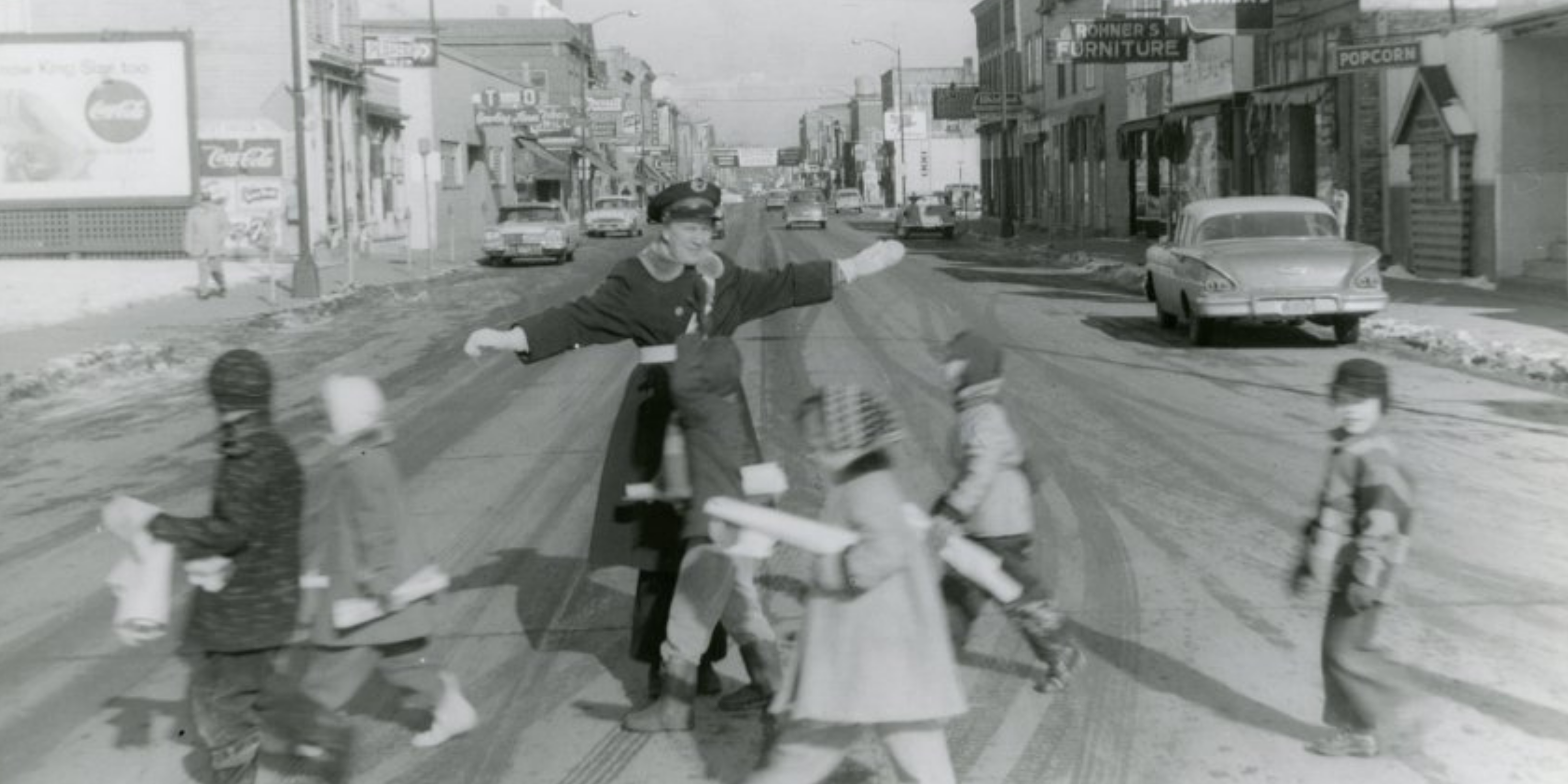 Police officer helping students cross the street at Oregon Street and 11th Avenue in 1957.